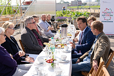 Joachim Steinbrück und Jürgen Dusel im Austausch mit Kolleginnen und Kollegen der Gemüsewerft und dem Projekt MitArbeit. Bei Sonnenschein sitzen die Teilnehmerinnen und Teilnehmer an einer Tafel und unterhalten sich. 