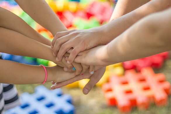 Sieben Kinderhände halten zusammen