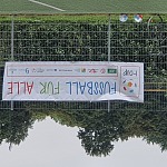 Banner am Zaun - I-Cup Fußball für alle – Zwei bunte Fußbälle liegen am Boden