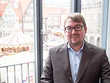 Arne Frankenstein vor den Fenstern der Bürgerschaft, im Hintergrund der Weihnachtsmarkt