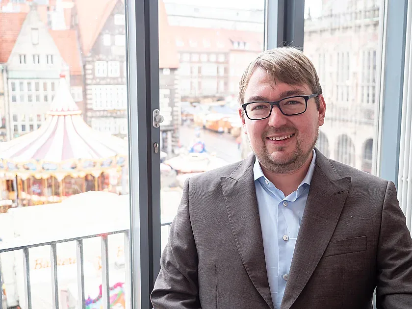 Arne Frankenstein vor den Fenstern der Bürgerschaft, im Hintergrund der Weihnachtsmarkt
