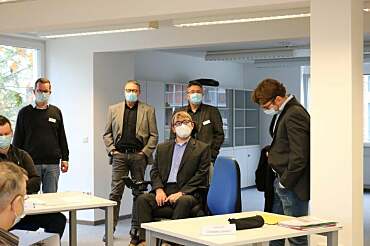 Arne Frankenstein und Kai Baumann im Gespräch mit dem Team von Friedehorst und dem Berufsförderungswerk in deren Geschäfsräumen. Alle tragen Masken.