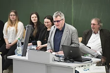 Das Foto wurde im März 2019 während der Veranstaltung "Schulische Inklusion in Bremen – Bilanz und Perspektiven" gemacht. Es zeigt Joachim Steinbrück während seines Vortrag. Er steht an einem Rednerpult. Hinter ihm sitzen drei Schülerinnen und ein Lehrer.