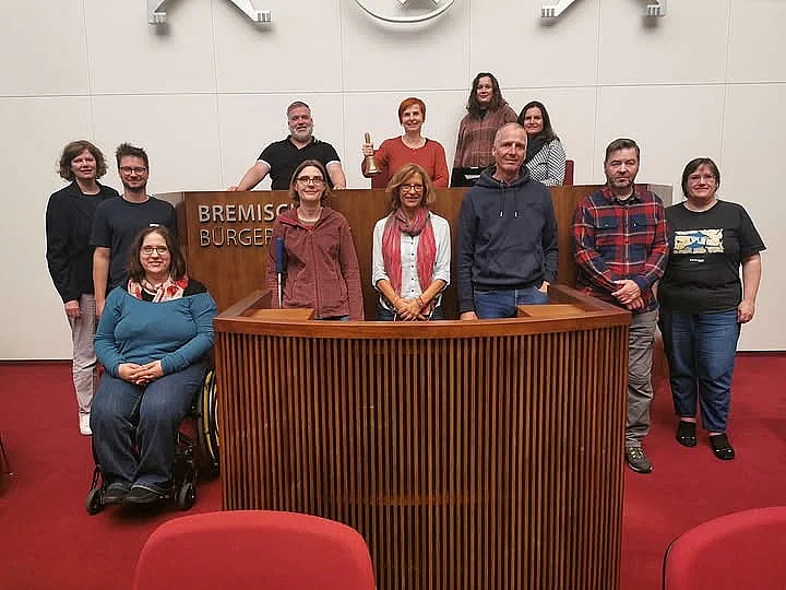 Gruppenbild der Teilnehmenden im Parlamentssaal vor und am Präsidentinnenpult 