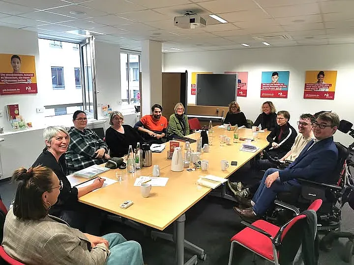 Die Teilnehmenden sitzen gemeinsam an einem langen Tisch