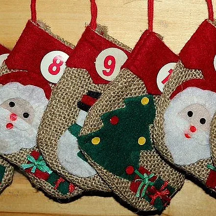 Ein Adventskalender aus Jutebeuteln, die mit Weihnachtsmotiven aus Filz geschmückt sind