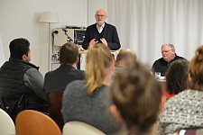Auf dem Foto ist Christoph Wündrich während seines Vortrags zu sehen. Er steht an einem Rednerpult. Daneben sitzt Horst Frehe an einem Tisch.