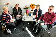 Auf der linken Seite eines Tisches sitzen Anja Stahmann und Hannelore Tempelmann. Auf der gegenüberliegenden Seite Bernd Giesecke sowie Joachim Steinbrück. Zwei Blumensträuße stehen am Ende des Tisches. Davor sind Kekse sowie Kaffeetassen zu sehen.