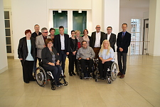 Gruppenbild während des 54. Treffen der Beauftragten für behinderte Menschen und der BAR in Kiel. Aufgenommen in der Eingangshalle des Tagungsorts. Insgesamt sind 14 Personen zu sehen. Drei davon nutzen einen Rollstuhl.