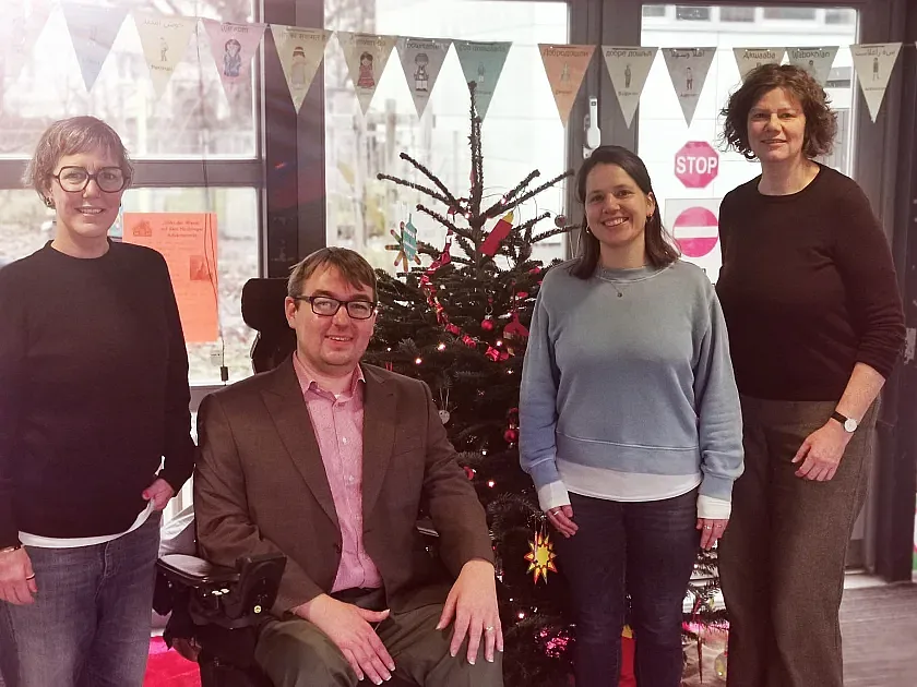 Die Teilnehmenden beim Besuch der Schule neben einem Weihnachtsbaum.