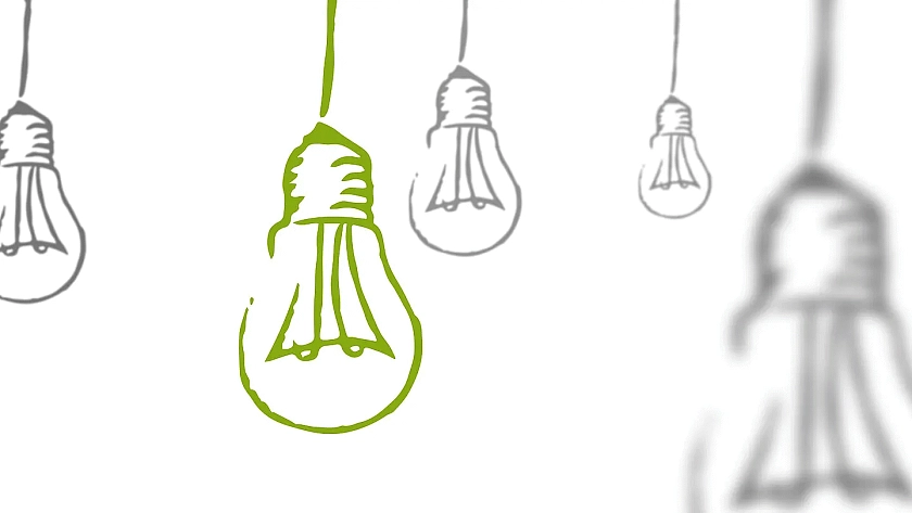 Eine grüne Glühbirne hängt zusammen mit mehreren grauen Glühbirnen von der Decke