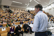 Das Foto zeigt den gut gefüllten Hörsaal der Universität Bremen. Im Vordergrund ist der Moderator, Robert Benckert zu sehen.