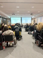 Blick von den hinteren Reihen über die Teilnehmenden zum Podium