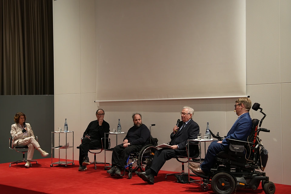 Blick auf die Diskussionsrunde nach dem Film. Antje Grotheer, J&uuml;rgen K&ouml;ster, Florian Grams, Friedrich Buhlrich und Arne Frankenstein sitzen nebeneinander vor der Leinwand auf dem roten Podium.