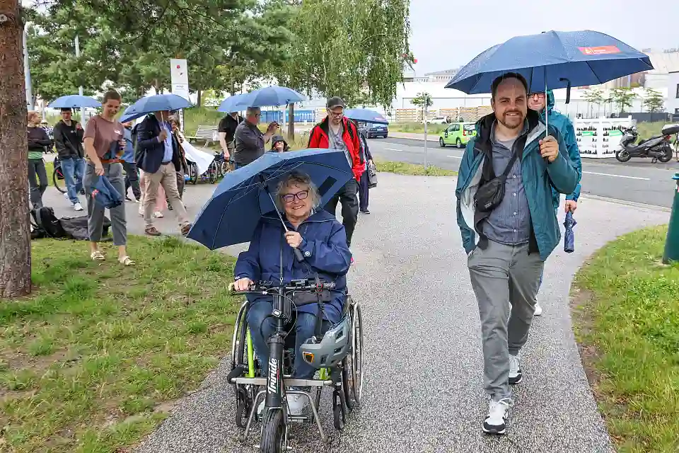 Zwei Teilnehmende mit Regenschirm auf dem Gel&auml;nde