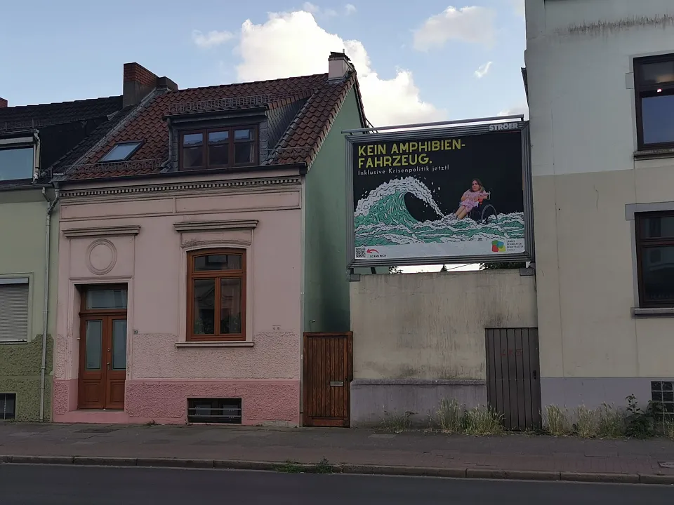 Das Plakat zwischen zwei H&auml;usern