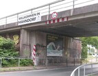 Das Plakat unter einer Eisenbahnbrücke