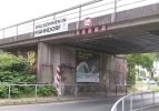 Das Plakat unter einer Eisenbahnbrücke