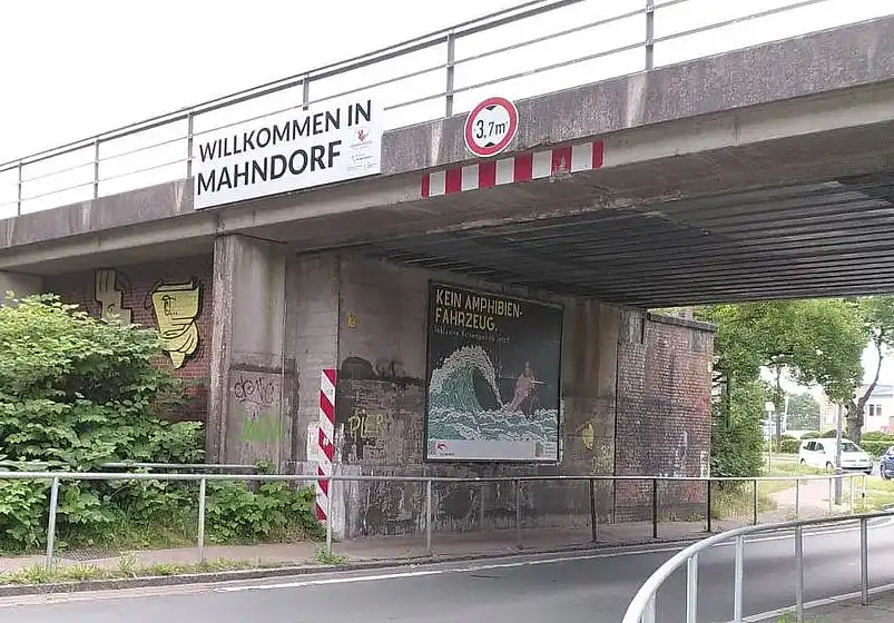 Das Plakat unter einer Eisenbahnbr&uuml;cke