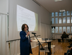 Die Leiterin der ambulanten Suchthilfe Bremen, Eva Carneiro Alves während ihres Grußwort. Sie steht an einem Rednerpunlt mit einem Mikrophon in der Hand.